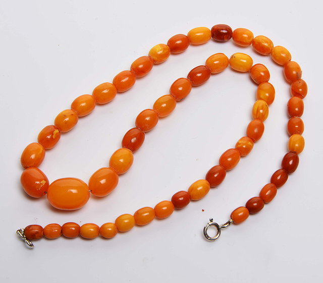 Appraisal: A GRADUATED AMBER BEAD NECKLACE each bead of oval form