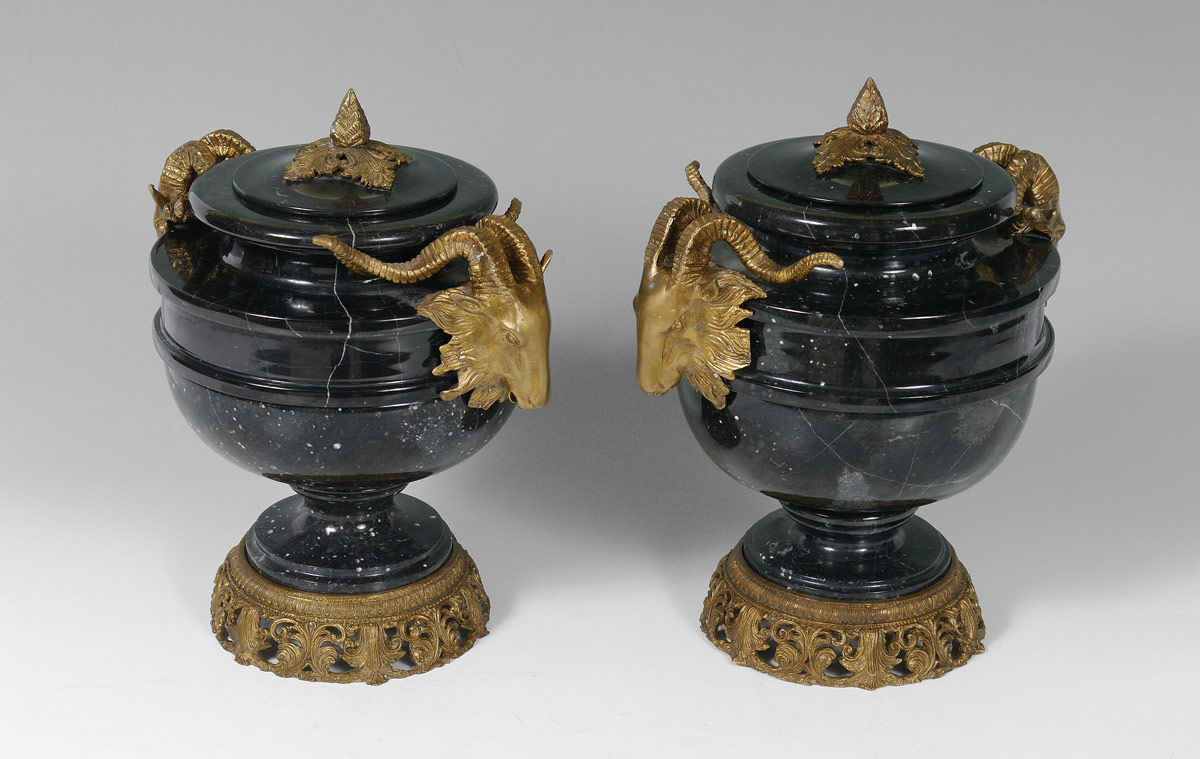 Appraisal: PAIR RAMS HEAD MASQUERON COVERED MARBLE URNS Black marble urns