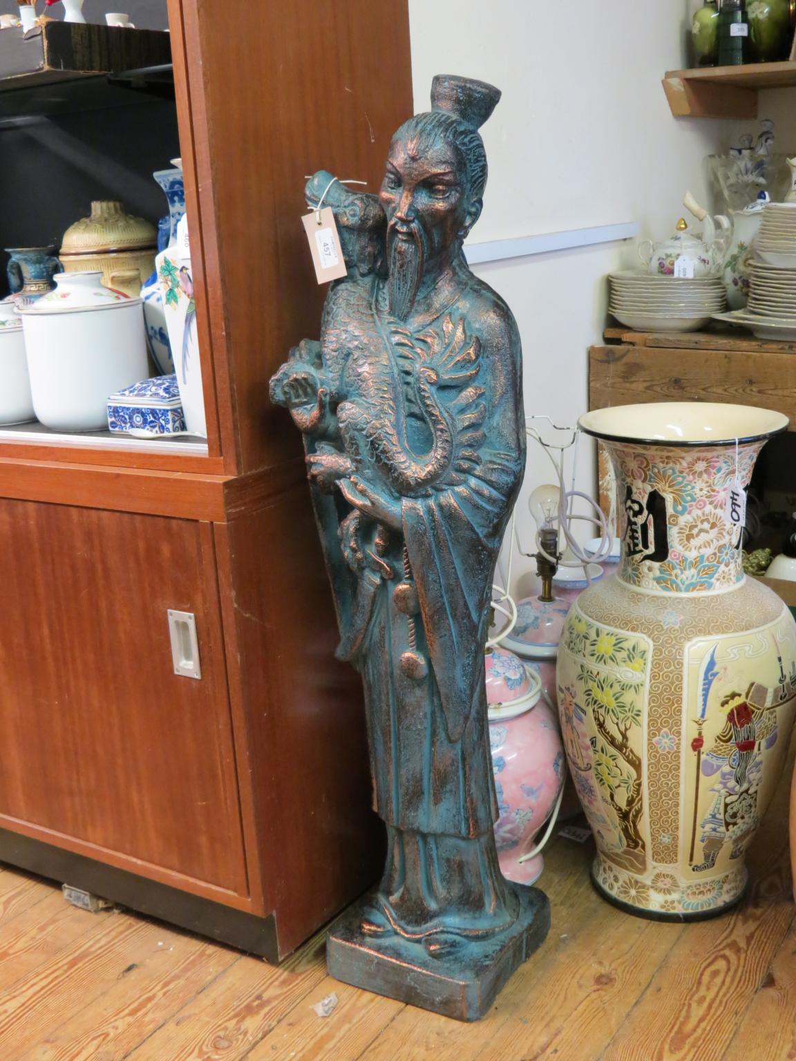 Appraisal: A modern bronze-effect Chinaman bearded character holding dog simulated verdigris