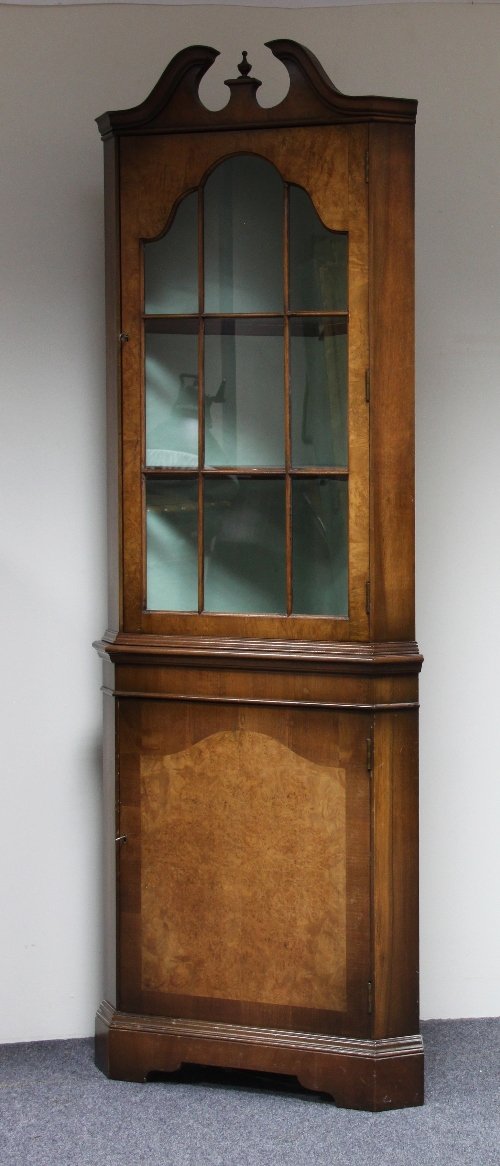 Appraisal: A walnut double corner cupboard with arched pediment