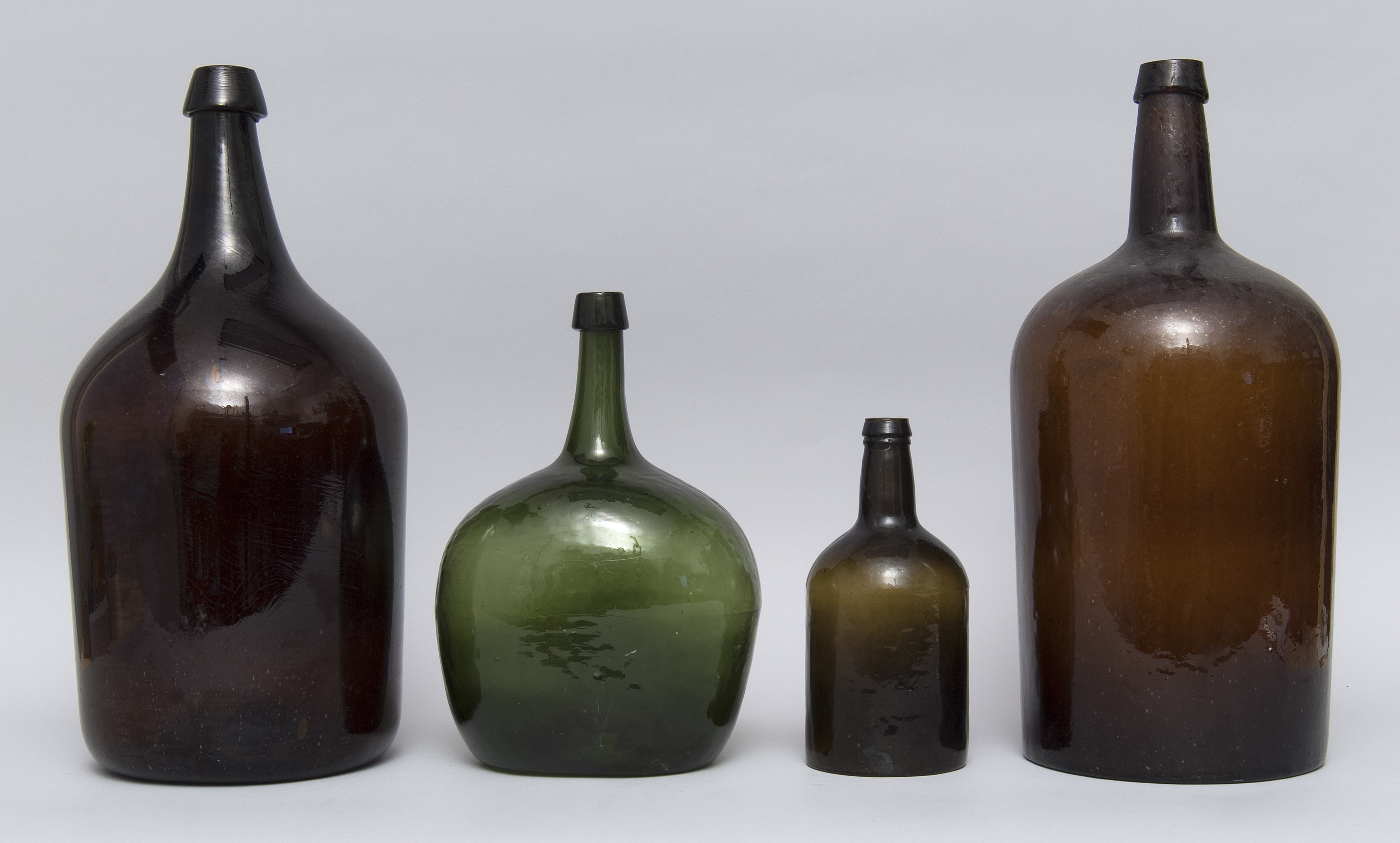 Appraisal: FOUR FREE-BLOWN AND BLOWN-MOLDED GLASS BOTTLES th CenturyIn green olive