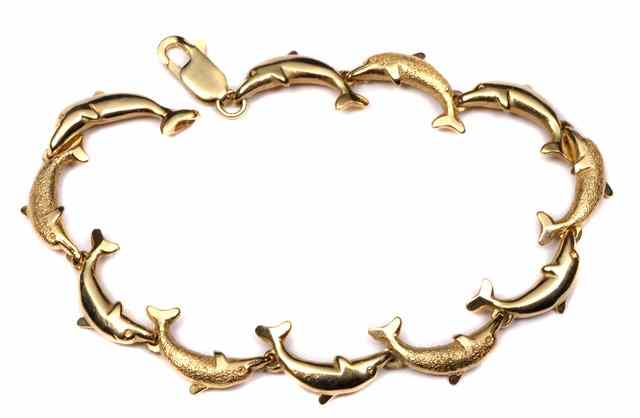 Appraisal: A GOLD BRACELET in the form of leaping dolphins stamped