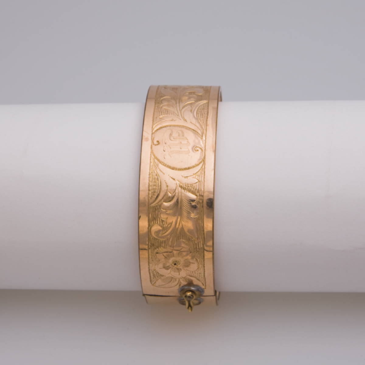 Appraisal: GOLD BANGLE Engraved in a floral pattern with a single