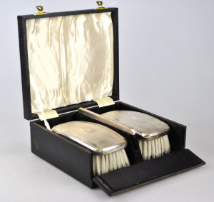 Appraisal: A cased pair of gentleman's hairbrushes and comb with engine-turned