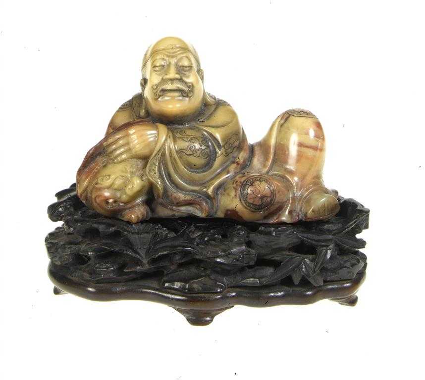 Appraisal: A CHINESE SOAPSTONE CARVING OF A LUOHAN reclining his left