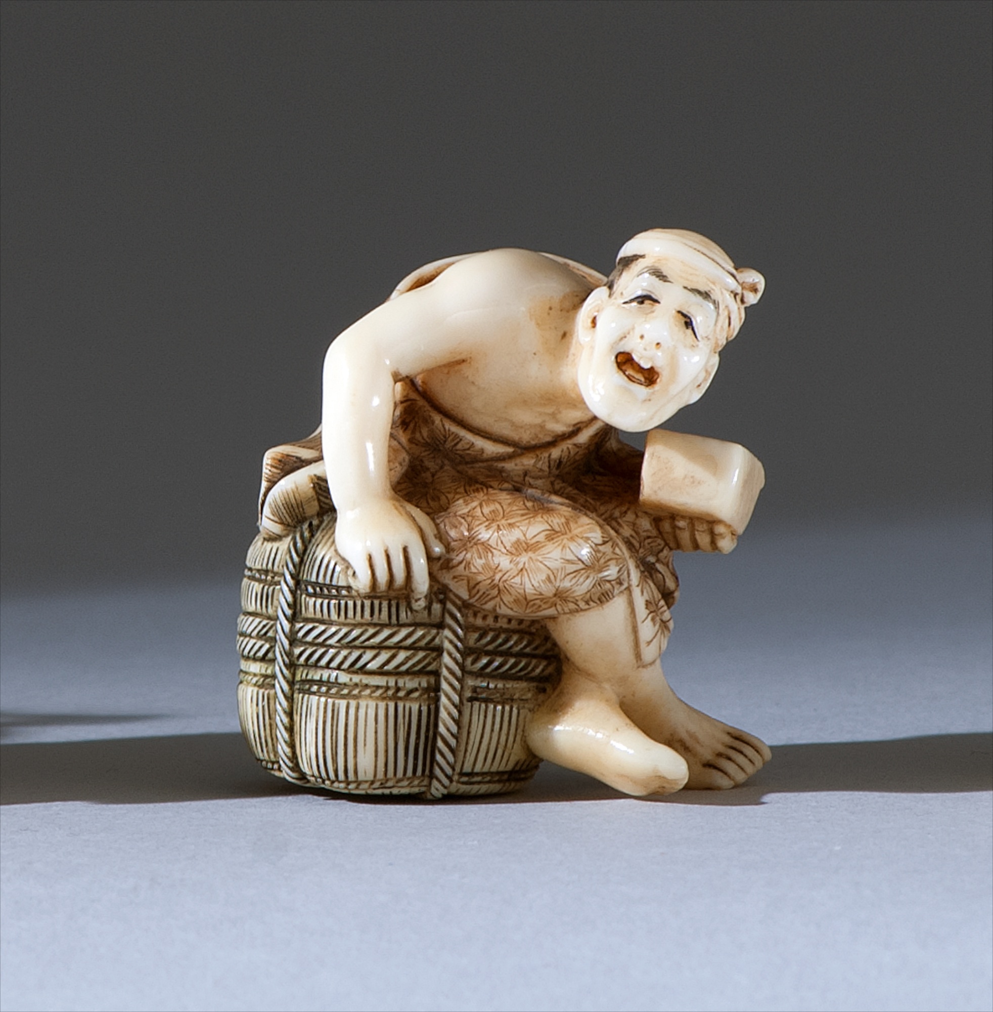 Appraisal: IVORY NETSUKE Depicting a laborer seated on a rice bale