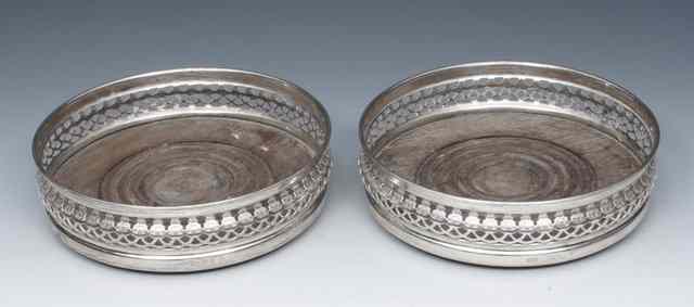 Appraisal: A PAIR OF SILVER BOTTLE COASTERS with pierced galleries and