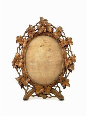 Appraisal: A Swiss carved wood oval frame decorated fruiting vines with