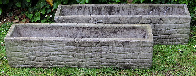 Appraisal: A PAIR OF RECTANGULAR CONCRETE PLANTERS cast with decoration in