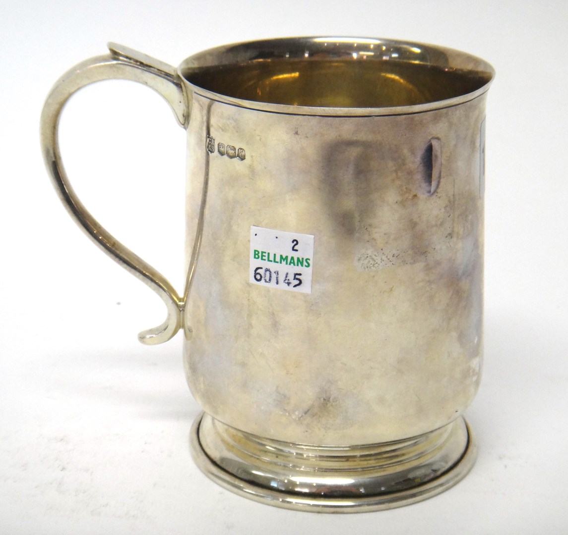 Appraisal: A silver mug with a curved handle on a circular