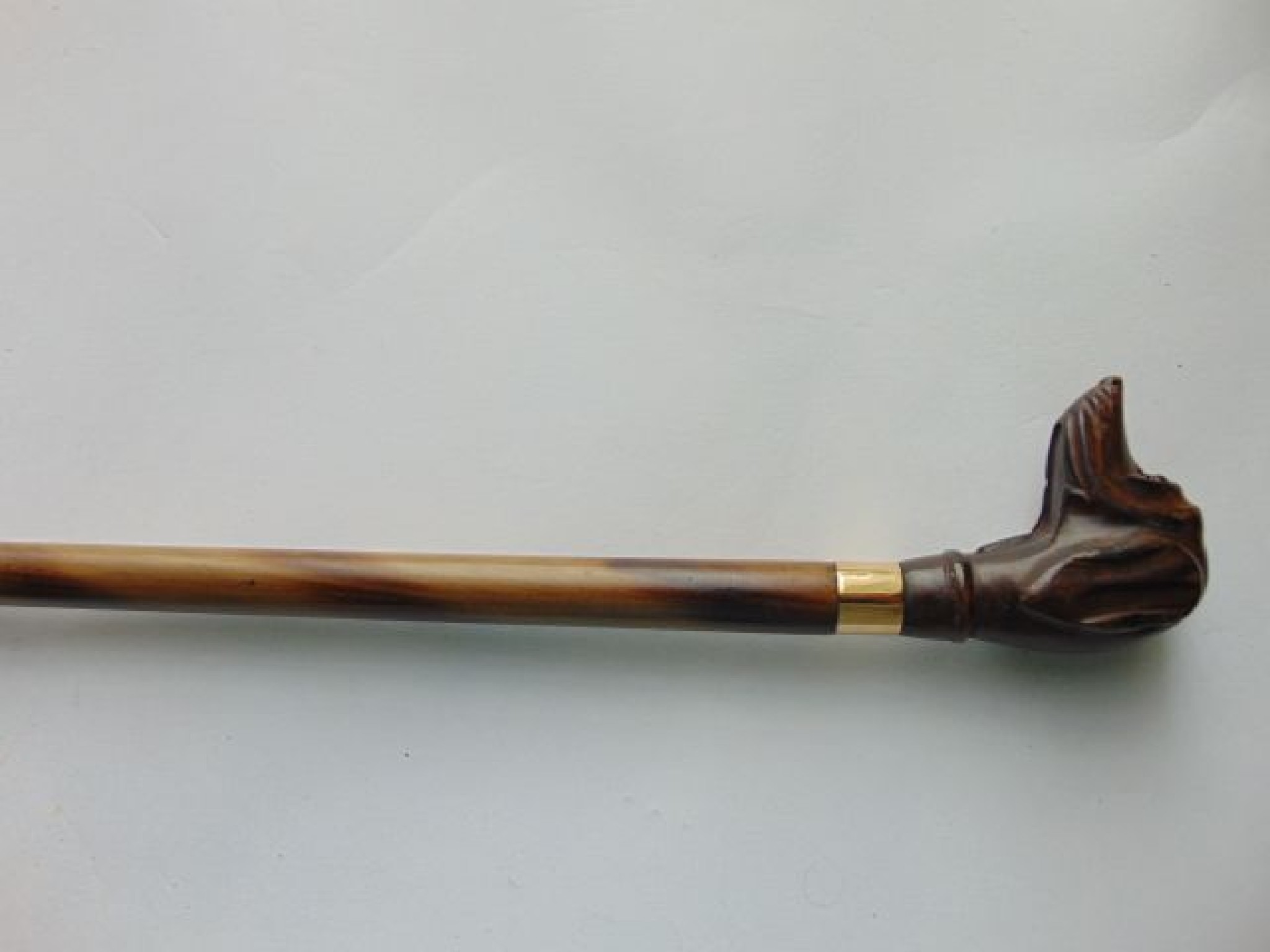 Appraisal: A slender polished timber cane the carved handle in the