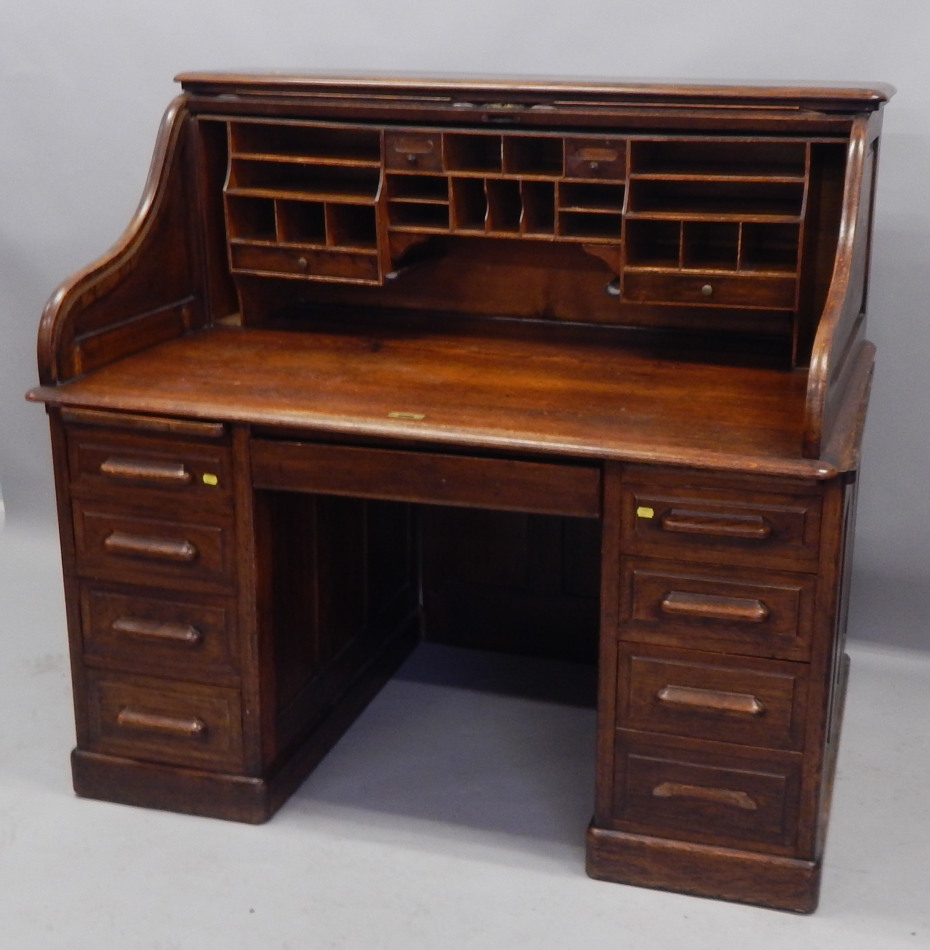 Appraisal: An early thC oak roll top desk with eight drawers