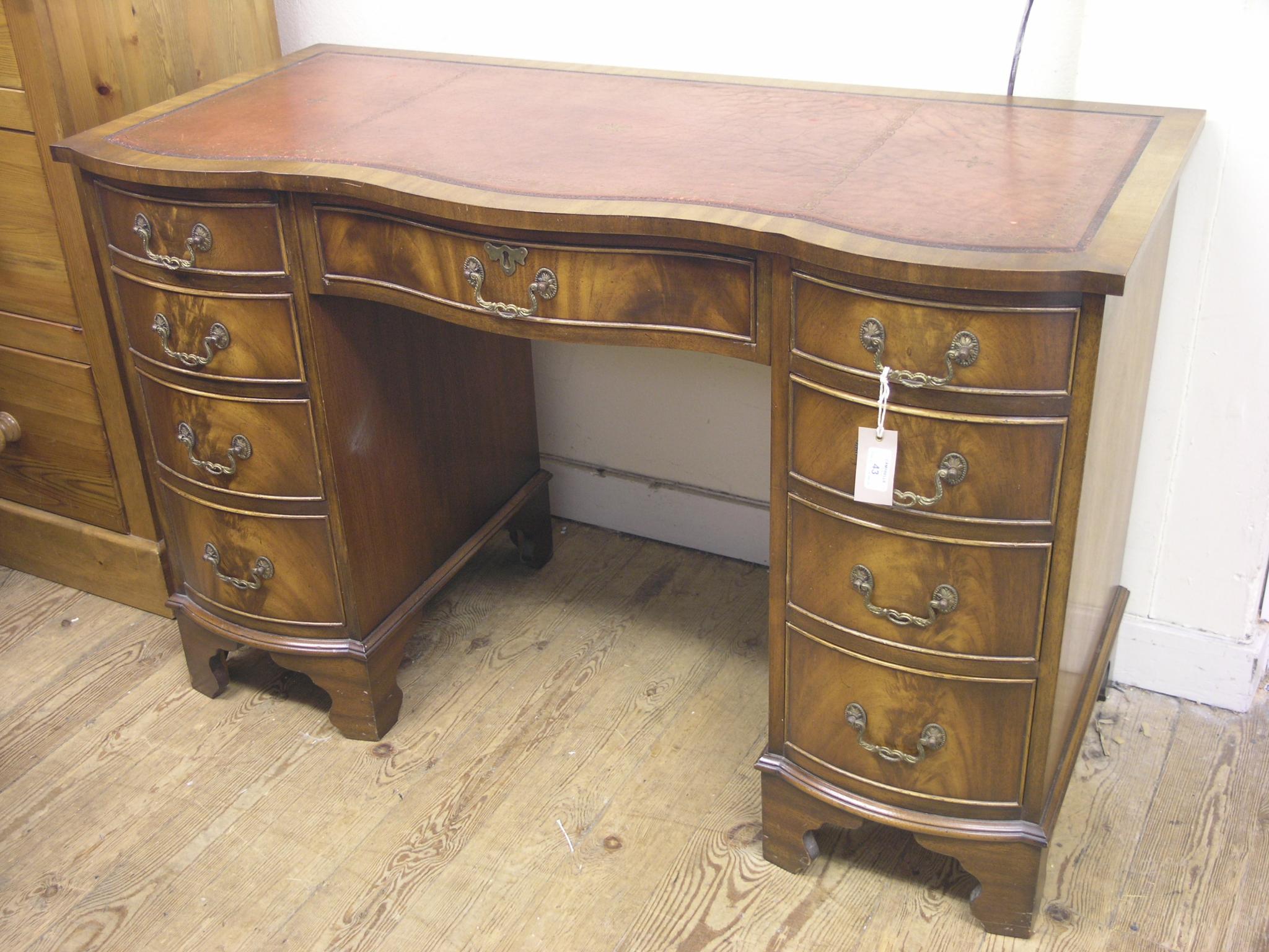 Appraisal: A reproduction mahogany desk serpentine-fronted with inset leather top kneehole