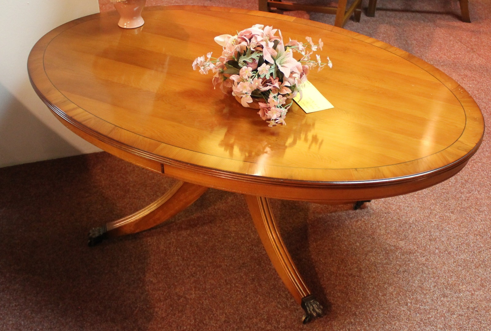 Appraisal: A yew finish oval coffee table with a wide crossbanded