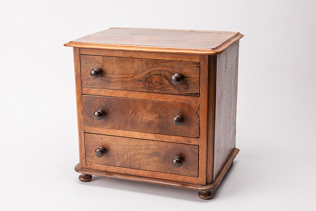 Appraisal: AN APPRENTICE WALNUT CHEST of three long drawers standing on