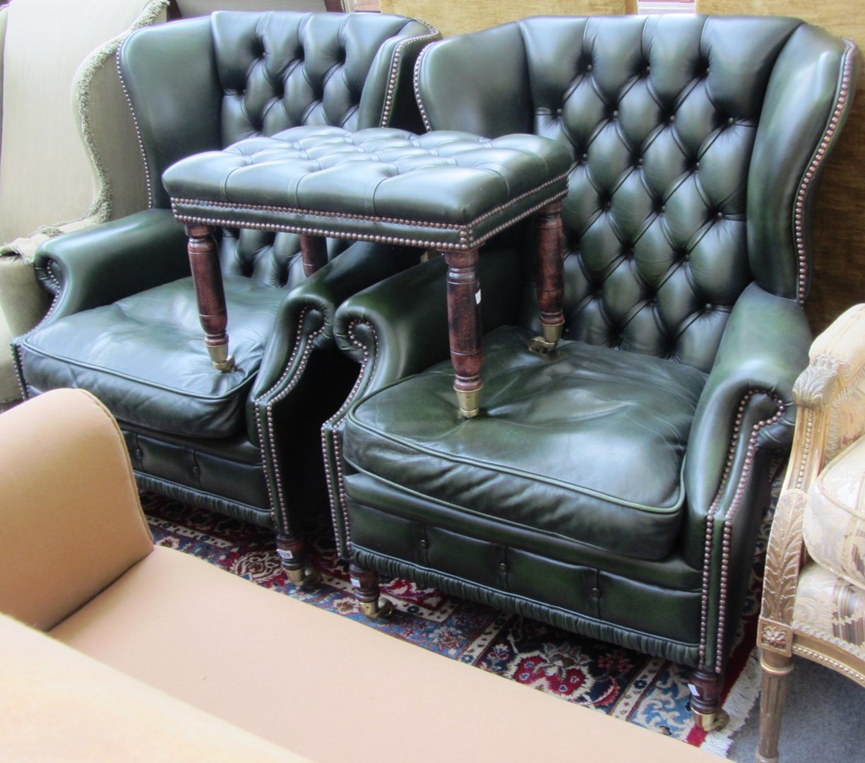 Appraisal: A pair of brass studded green leather upholstered wingback armchairs