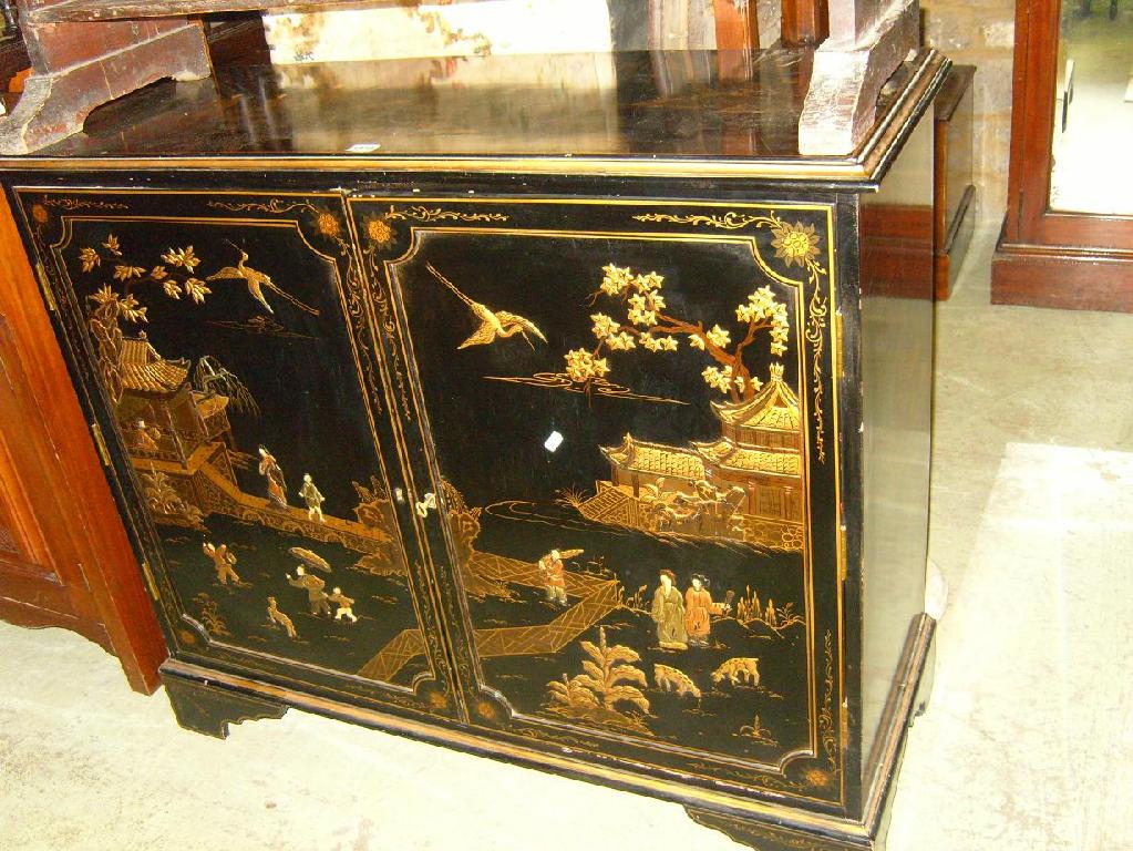 Appraisal: An ebonised side cupboard enclosed by two panelled doors on