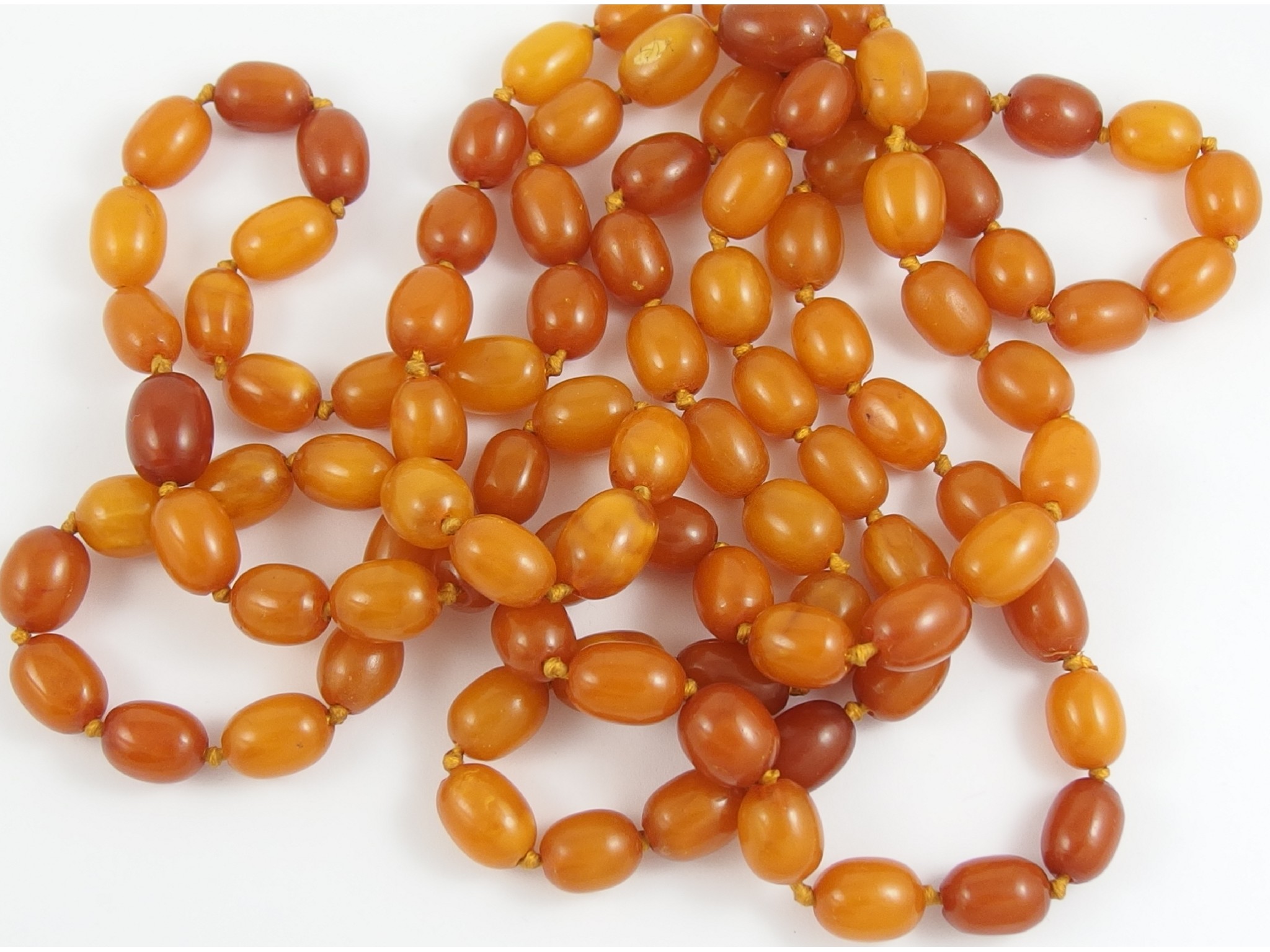 Appraisal: An opera length of amber coloured beadsof opaque orange colour