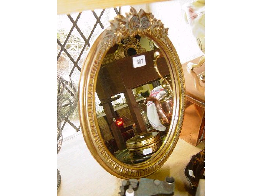 Appraisal: An oval framed mirror in the Barbola style with floral