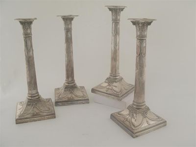 Appraisal: A set of four Edwardian column candlesticks on square bases