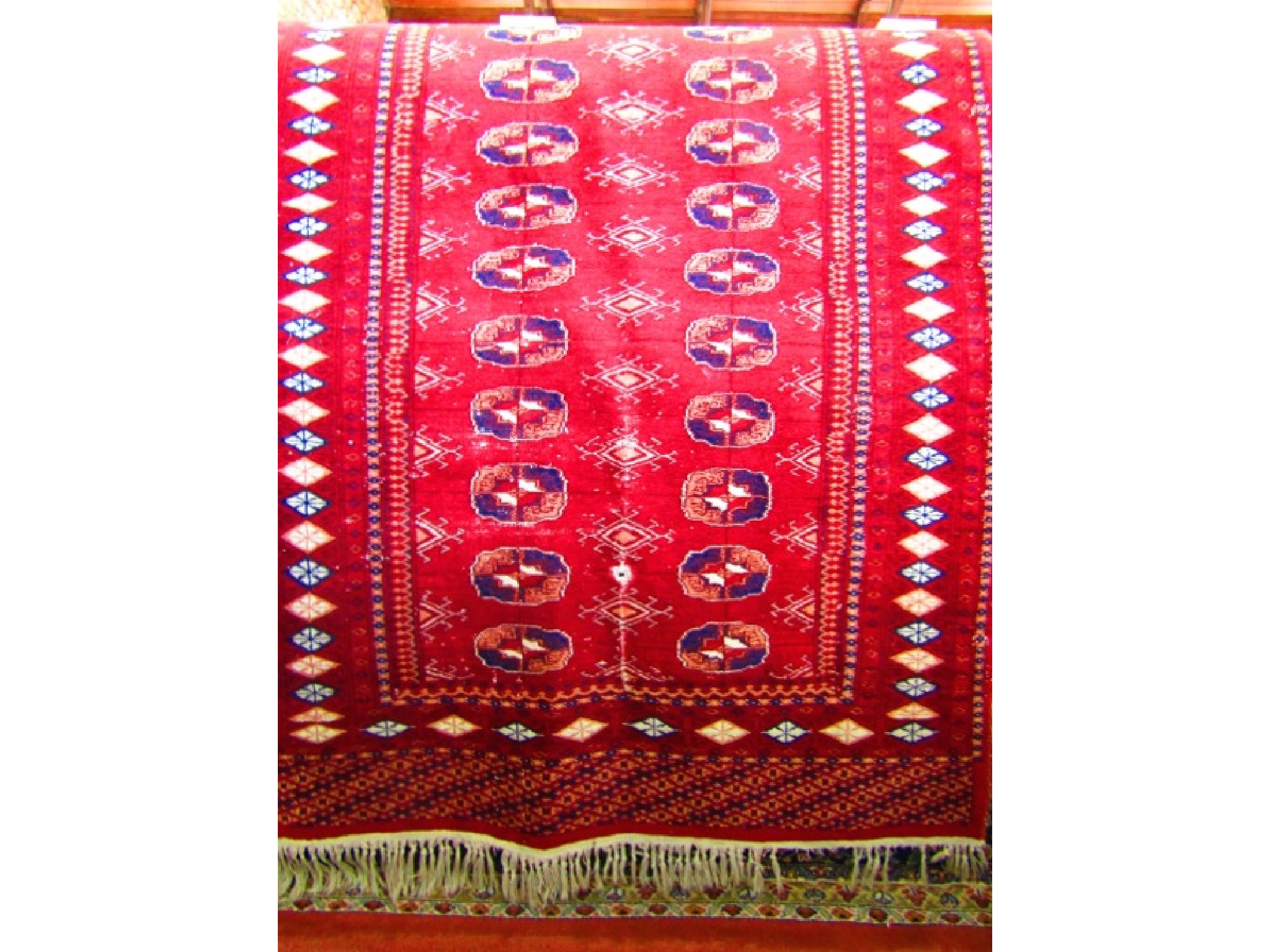 Appraisal: A small red ground Persian style wool rug with concentric