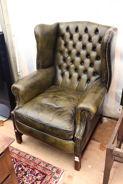 Appraisal: A GREEN LEATHER UPHOLSTERED WING BACK ARMCHAIR standing on square