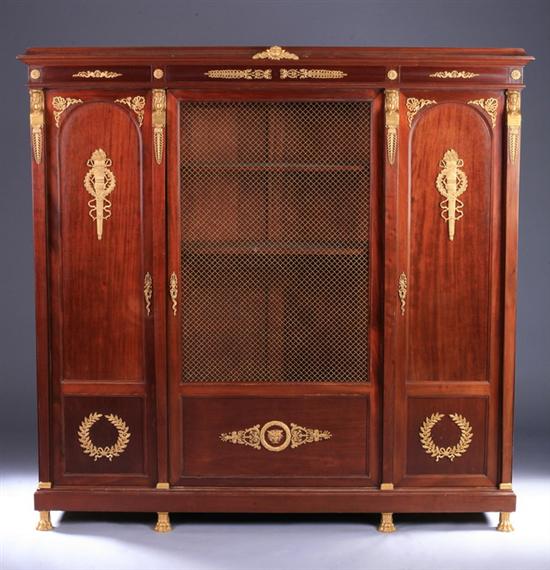 Appraisal: EMPIRE MAHOGANY GRILL-FRONT THREE-DOOR BIBLIOTHEQUE th century with gilt-metal laurel