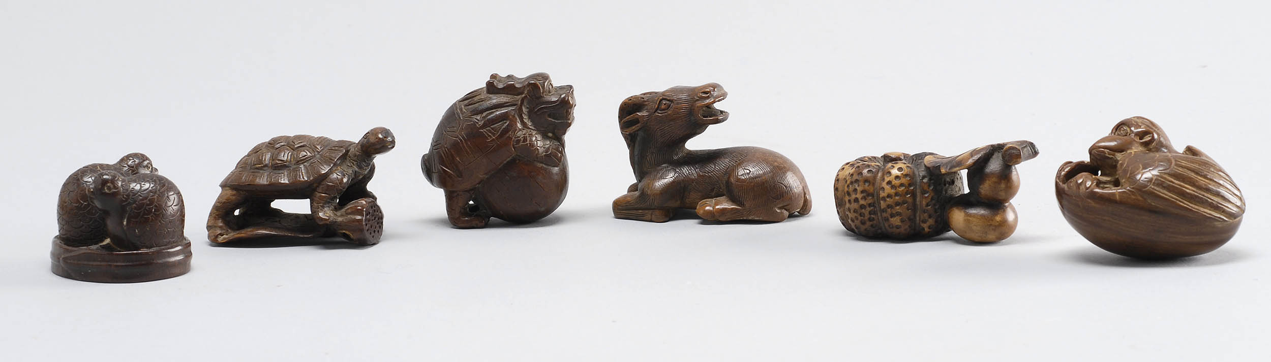 Appraisal: SIX WOOD NETSUKE th CenturyReclining stag turtle on lotus tengu