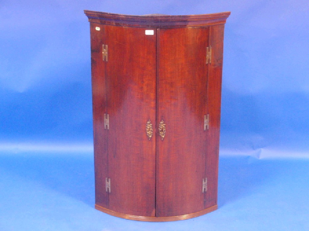 Appraisal: A Georgian figured mahogany cylinder fronted hanging corner cupboard moulded