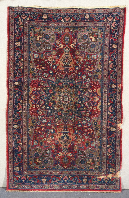 Appraisal: A PERSIAN RED GROUND RUG decorated a central star medallion