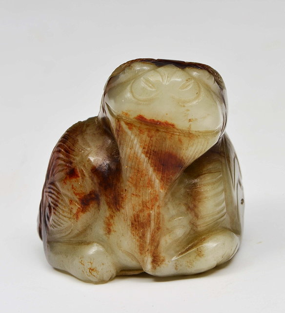 Appraisal: A CHINESE CELADON AND MOTTLED JADE PEBBLE carved as a