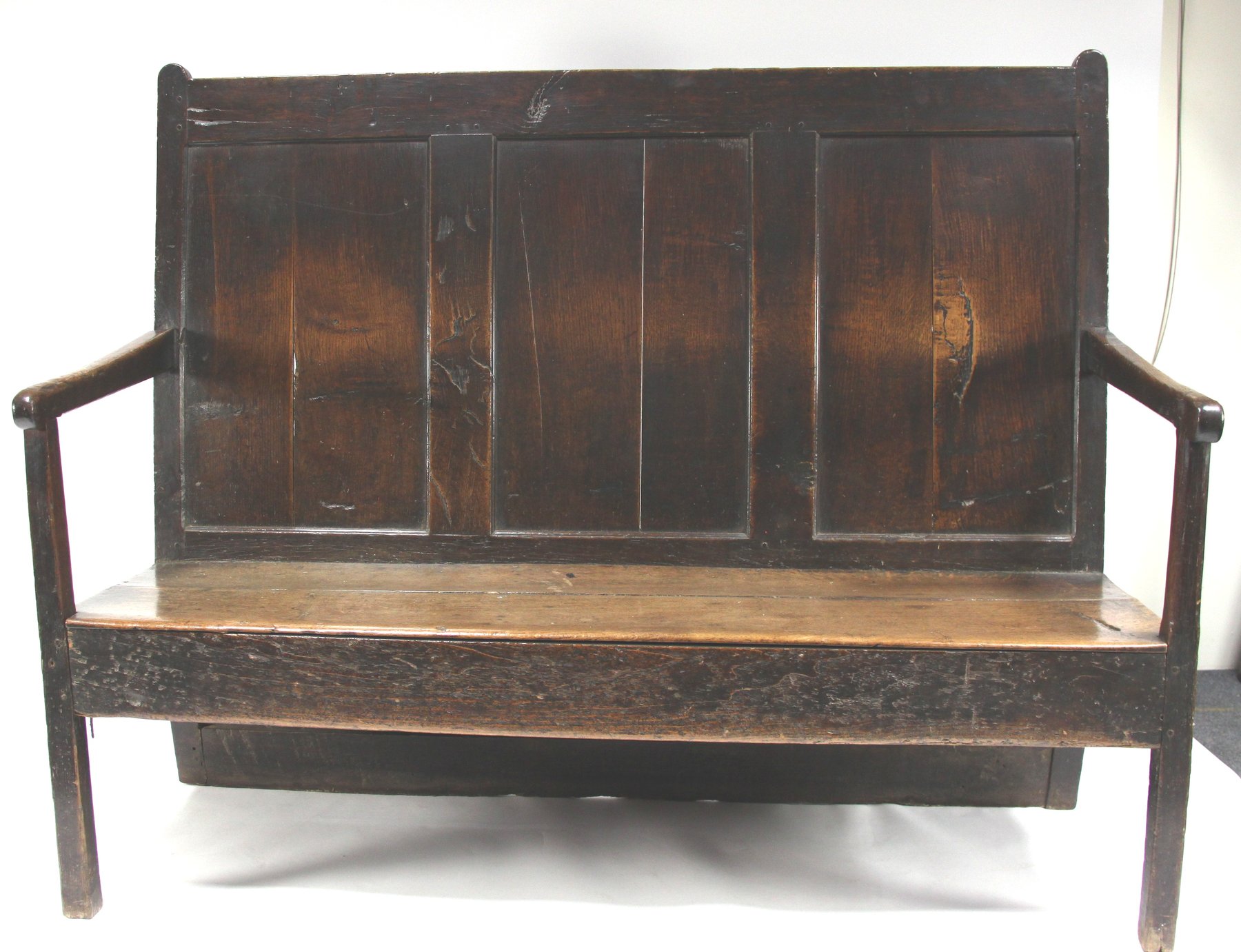 Appraisal: An oak settle with three panelled back to base with