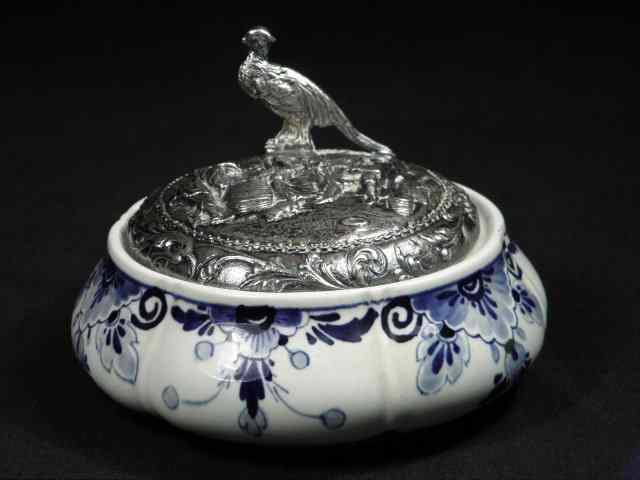 Appraisal: A Delft ceramic dresser powder jar with a silver plated