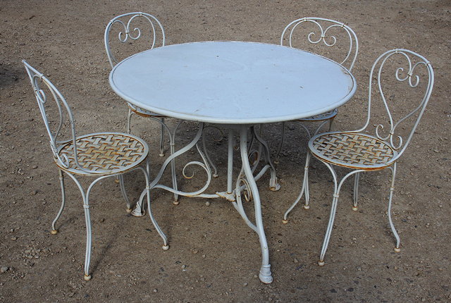 Appraisal: A CIRCULAR WROUGHT IRON CREAM PAINTED GARDEN TABLE with scrolling