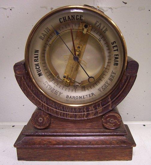 Appraisal: An aneroid barometer in a circular case on an oak