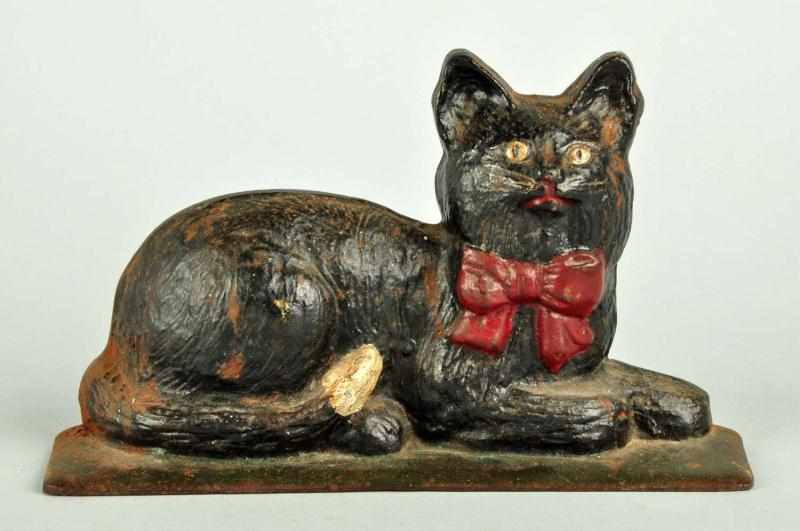 Appraisal: Cast Iron Lying Down Cat with Red Bow Doorstop Description