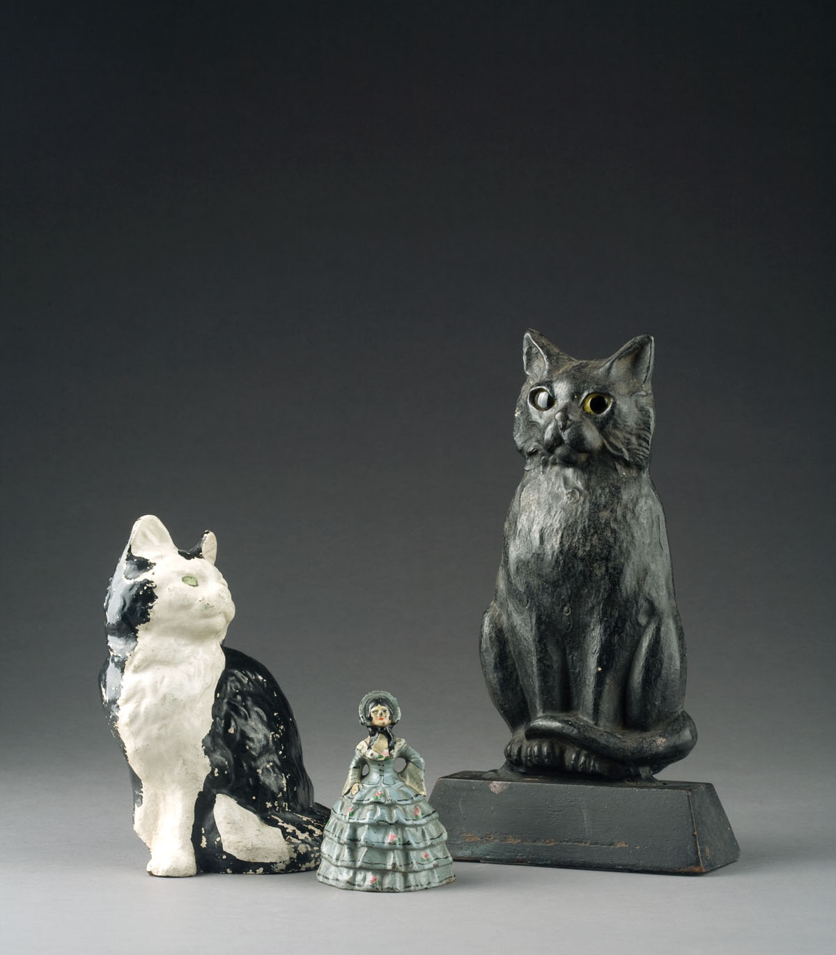 Appraisal: CAST-IRON HOOPSKIRT LADY GLASS-EYED CAT AND SEATED CAT DOORSTOPS