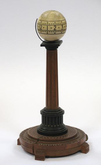 Appraisal: A BREVET IVORY GLOBE-SHAPED CLOCK sat atop a single wooden