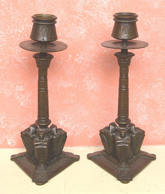 Appraisal: A PAIR OF EGYPTIAN REVIVAL BRONZE CANDLESTICKS with shaped sconces