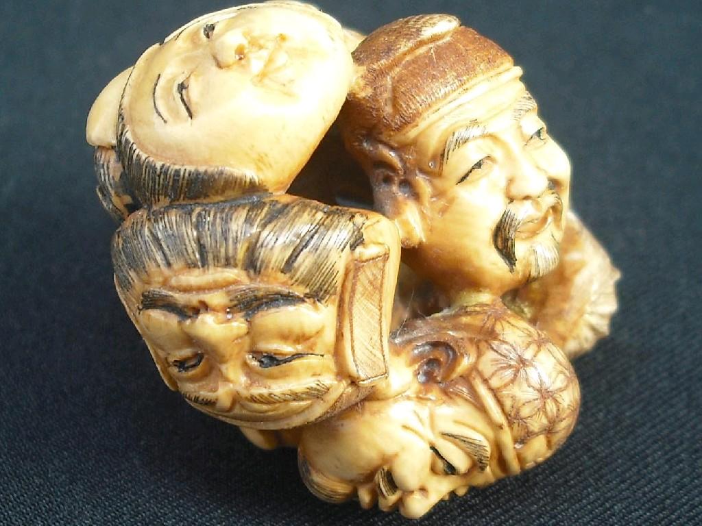 Appraisal: Carved ivory mask netsuke pierced with seven faces of differing