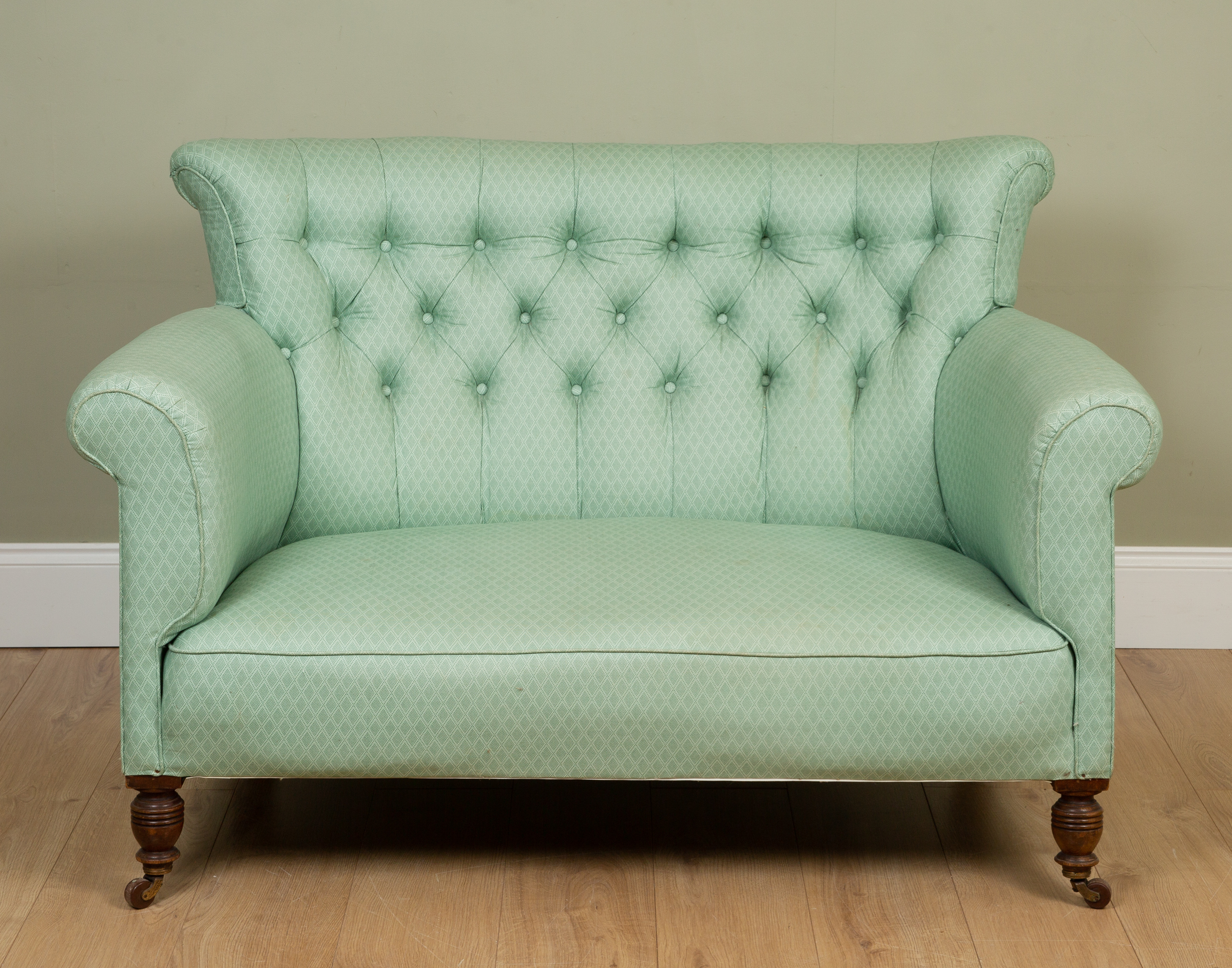 Appraisal: A small green button back sofa with scrolling arms turned