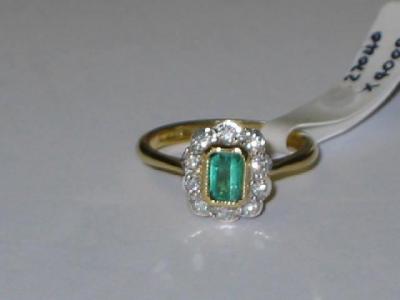 Appraisal: AN EMERALD AND DIAMOND CLUSTER RING the trapp cut emerald