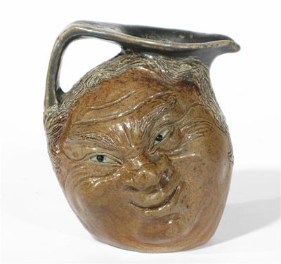 Appraisal: A Martin Brothers stoneware face jug each side cast and