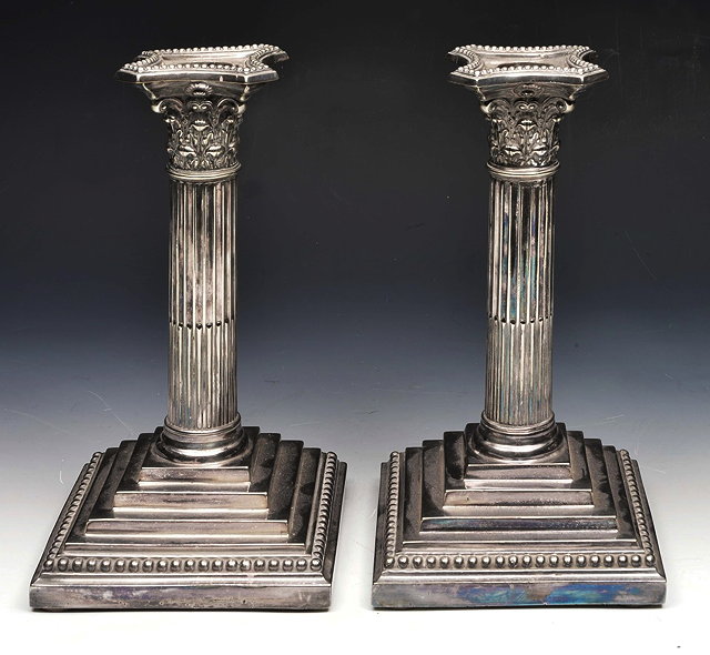 Appraisal: A PAIR OF SILVER PLATED CORINTHIAN COLUMN CANDLESTICKS on square