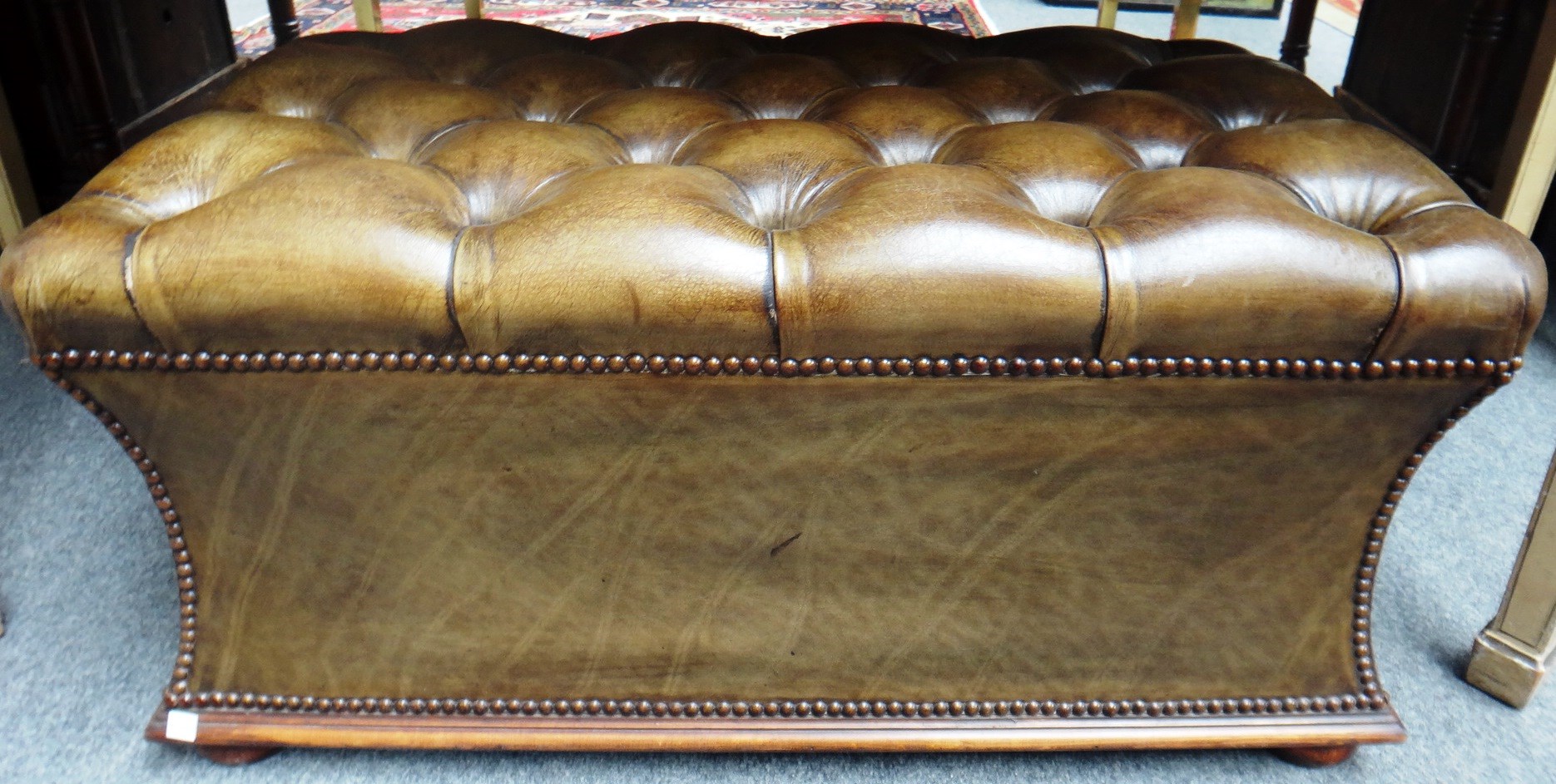 Appraisal: A leather upholstered stool of sarcophagus form on bun feet