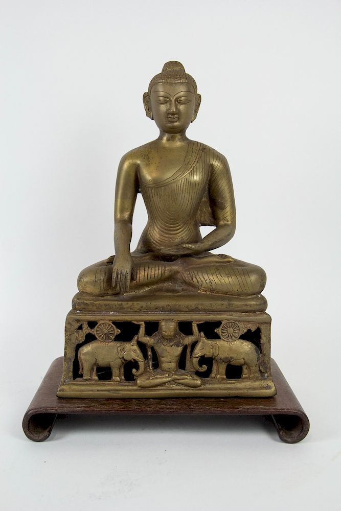 Appraisal: A Brass Indian Figure of Sakyamuni The buddha sits atop