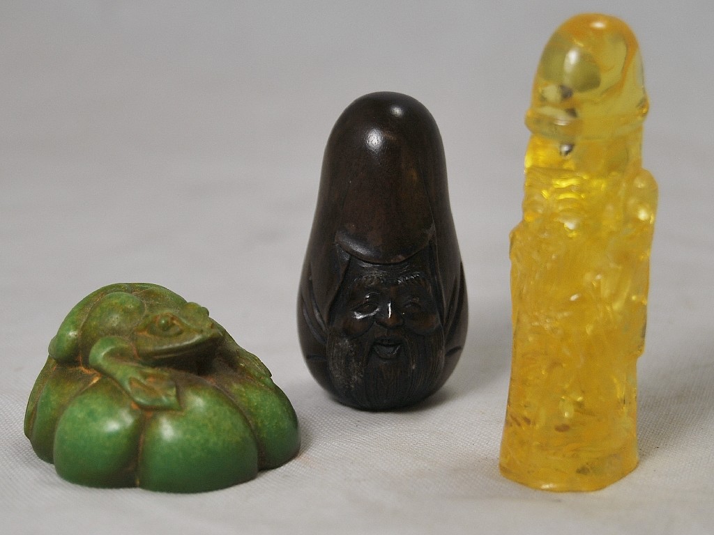 Appraisal: Two Chinese netsukes and a simulated amber lingam carved as