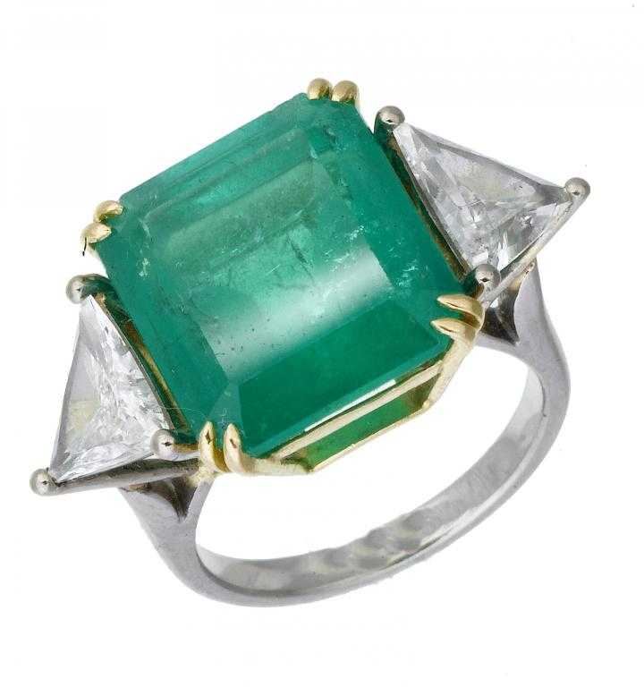 Appraisal: AN EMERALD AND DIAMOND RING the step cut emerald flanked