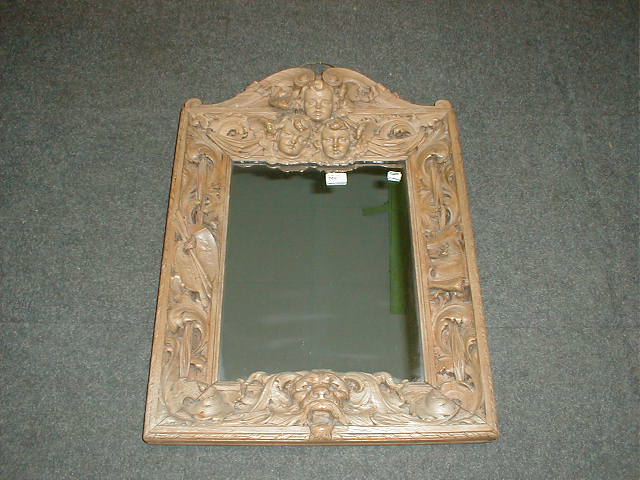 Appraisal: A thC carved walnut mirror with angel mask deep relief