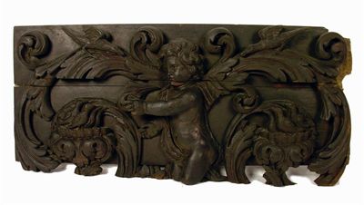 Appraisal: An th century stained oak carving of a putto flanked